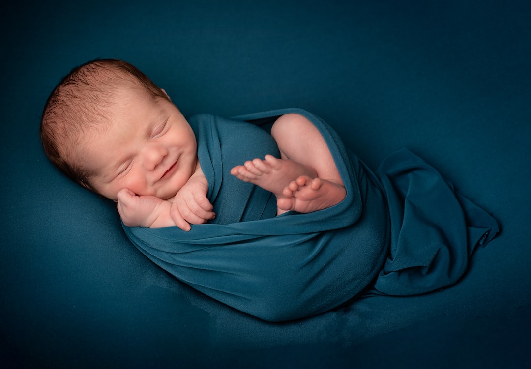 baby lying on blue textile mDiFpFl jTs jpg