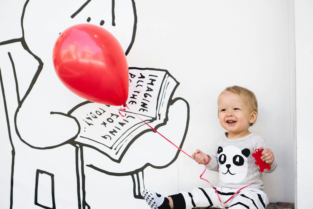 smiling toddler holding red balloon slpibXIhizI jpg
