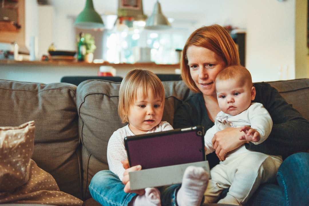 two babies and woman sitting on sofa while holding baby and watching on tablet UH xs FizTk jpg